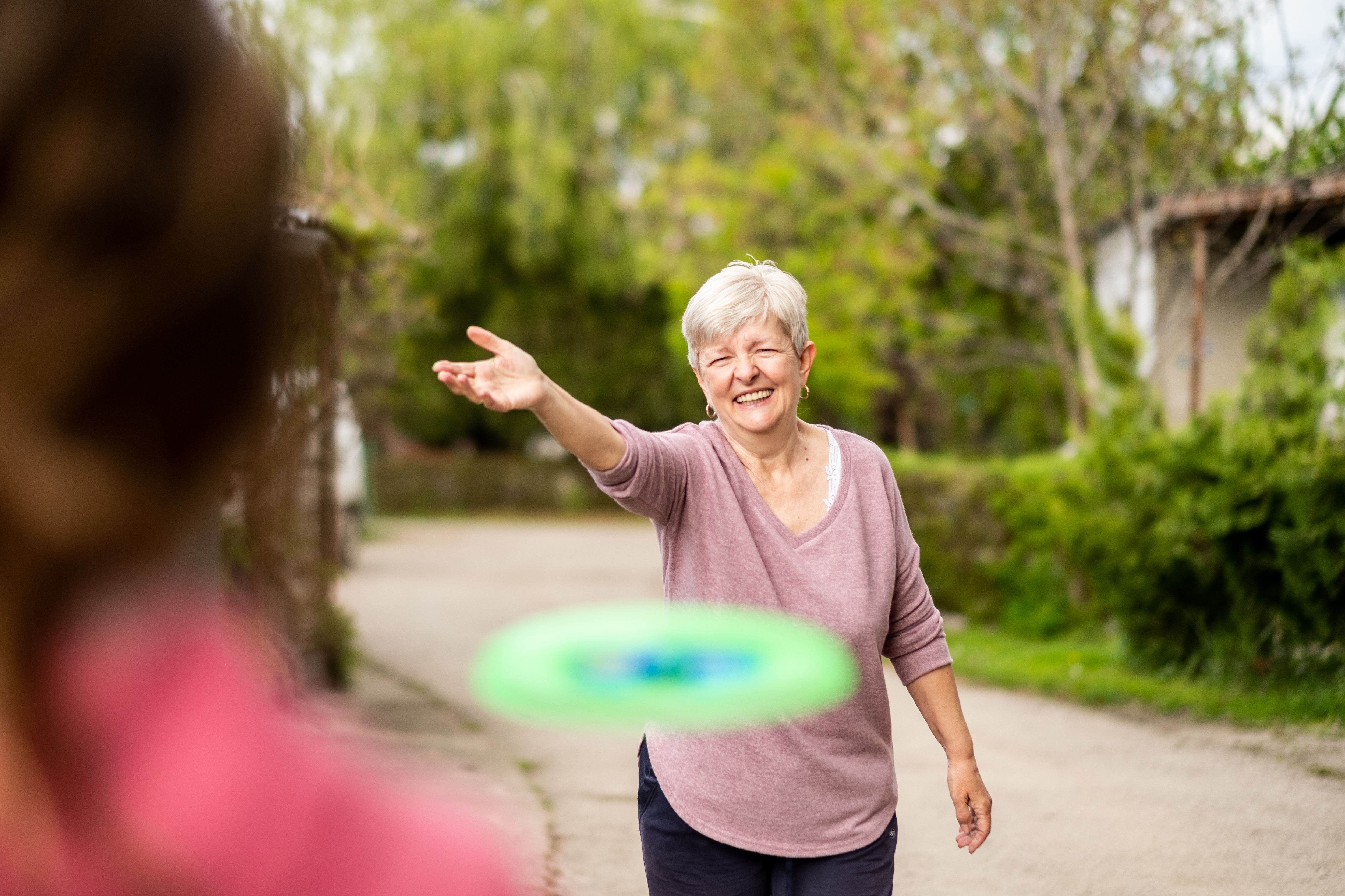 Grandmother and granddaughter playing with frisbee outside.