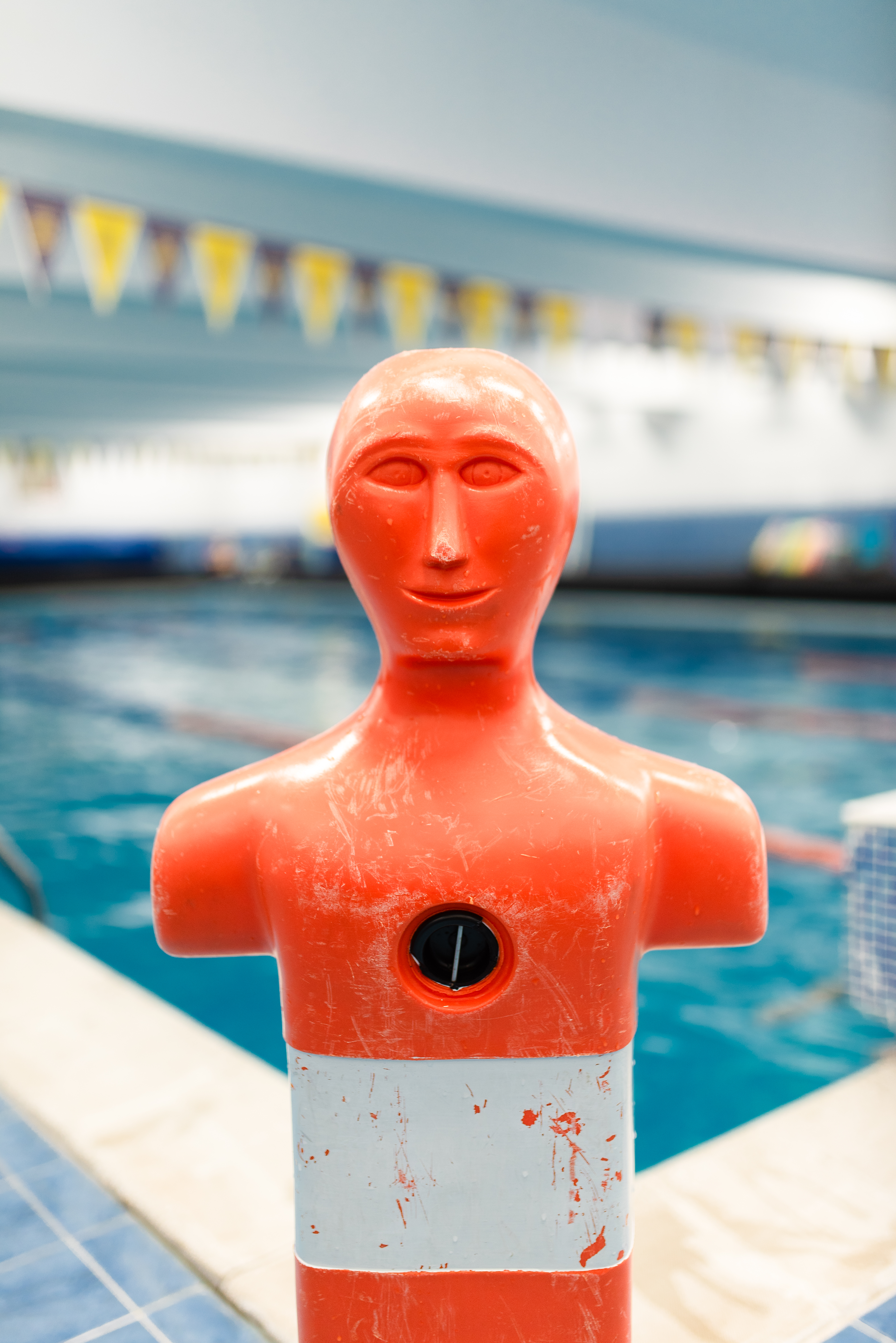 Portrait stock photo of a life saving practice dummy in front of indoors swimming pool