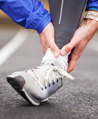 Cropped shot of a young man holding his ankle in pain while running.