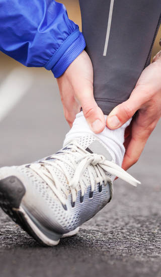 Cropped shot of a young man holding his ankle in pain while running.