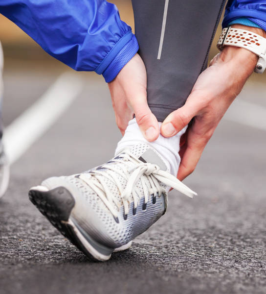 Cropped shot of a young man holding his ankle in pain while running.