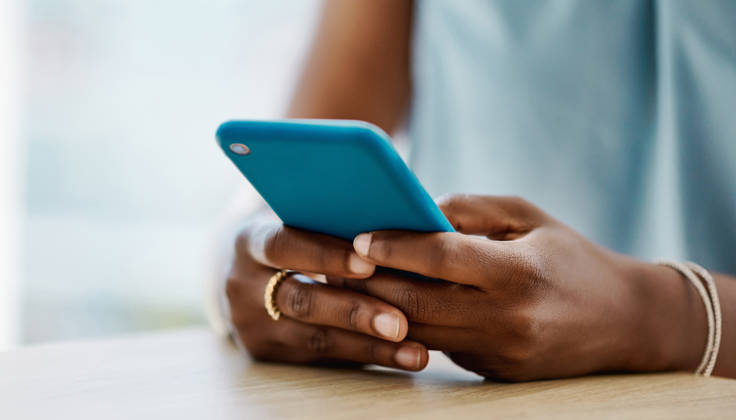 Afrikaanse vrouw met gsm, enkel handen zichtbaar