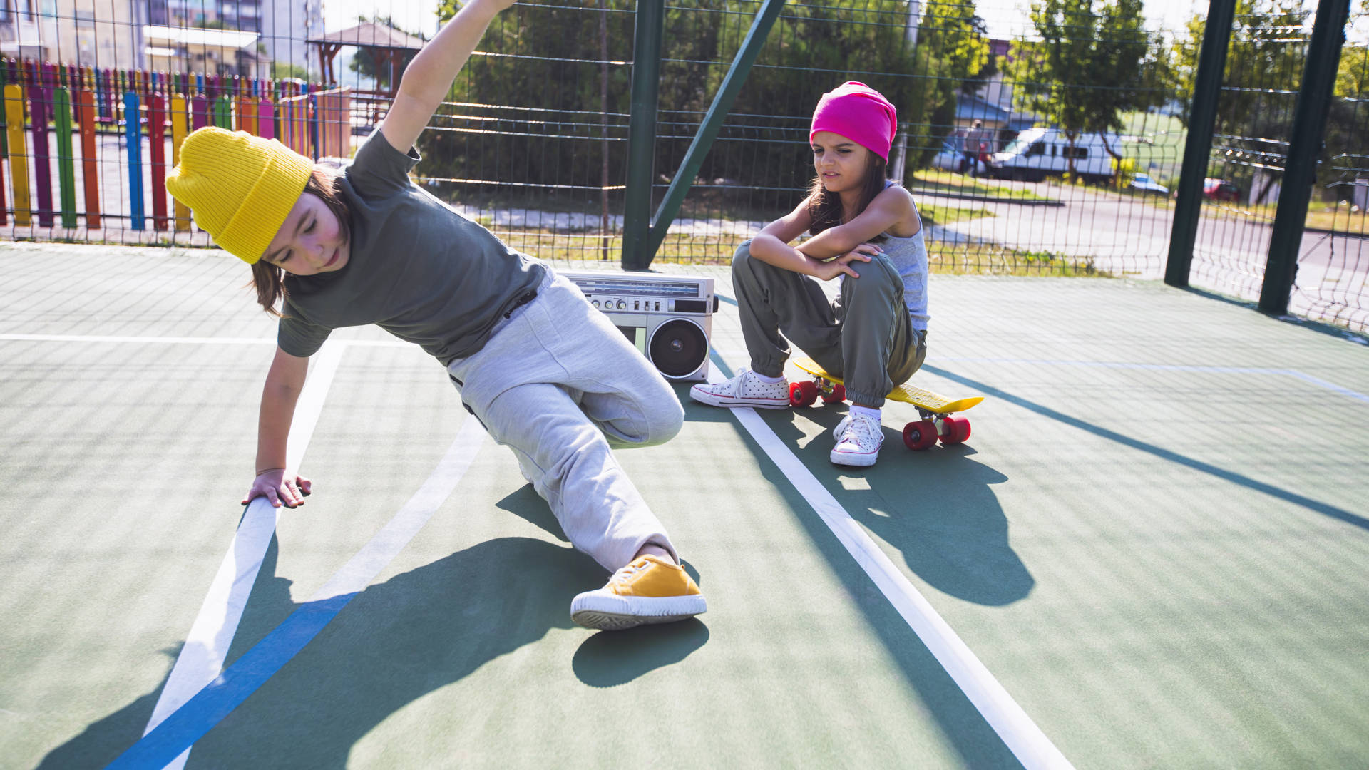 Two happy children listening music, having fun and dancing breakdance on a playground.