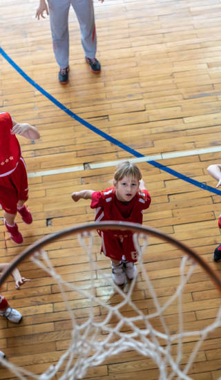 Meisjesteam gooit bal naar basketring in sporthal