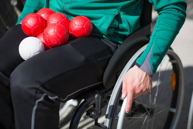 man in rolstoel met bocciaballen op schoot
