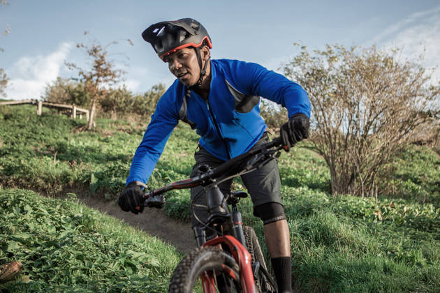 Man rijdt met mountainbikefiets door de weilanden