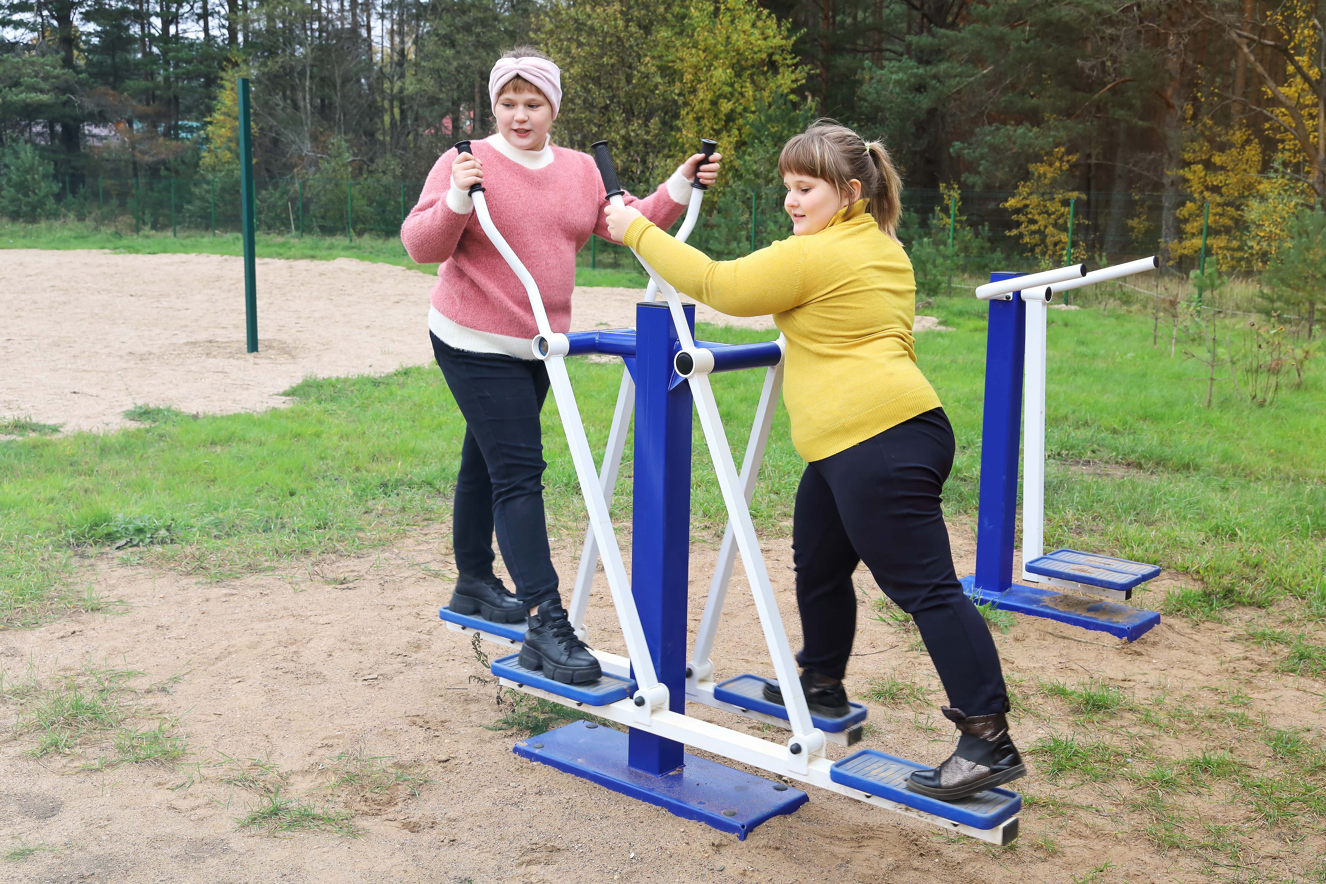 Two chubby girls performs sports exercises on street simulators, motivation to healthy lifestyle