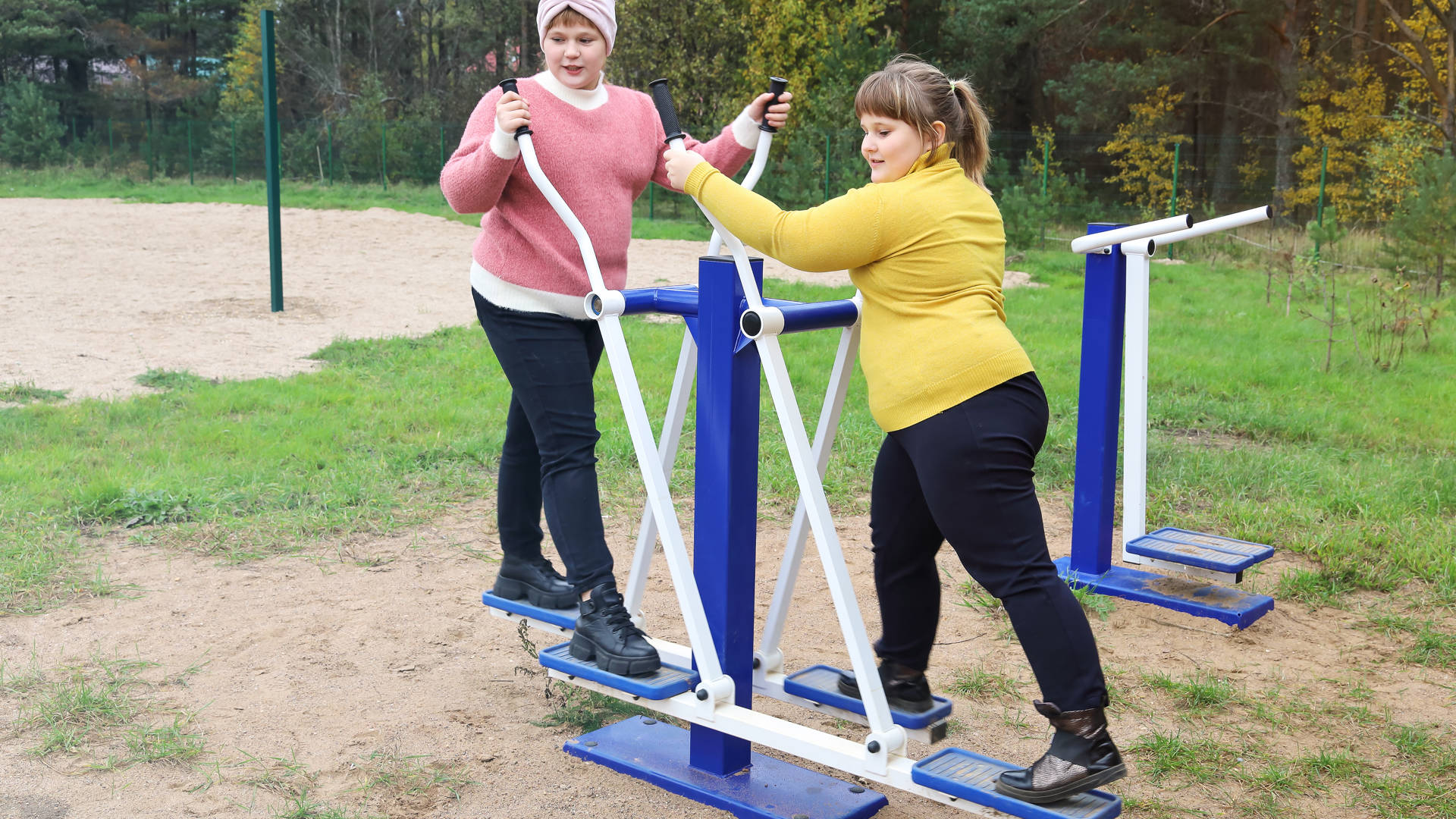 Two chubby girls performs sports exercises on street simulators, motivation to healthy lifestyle