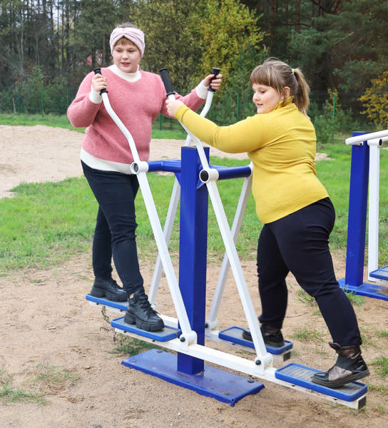 Two chubby girls performs sports exercises on street simulators, motivation to healthy lifestyle