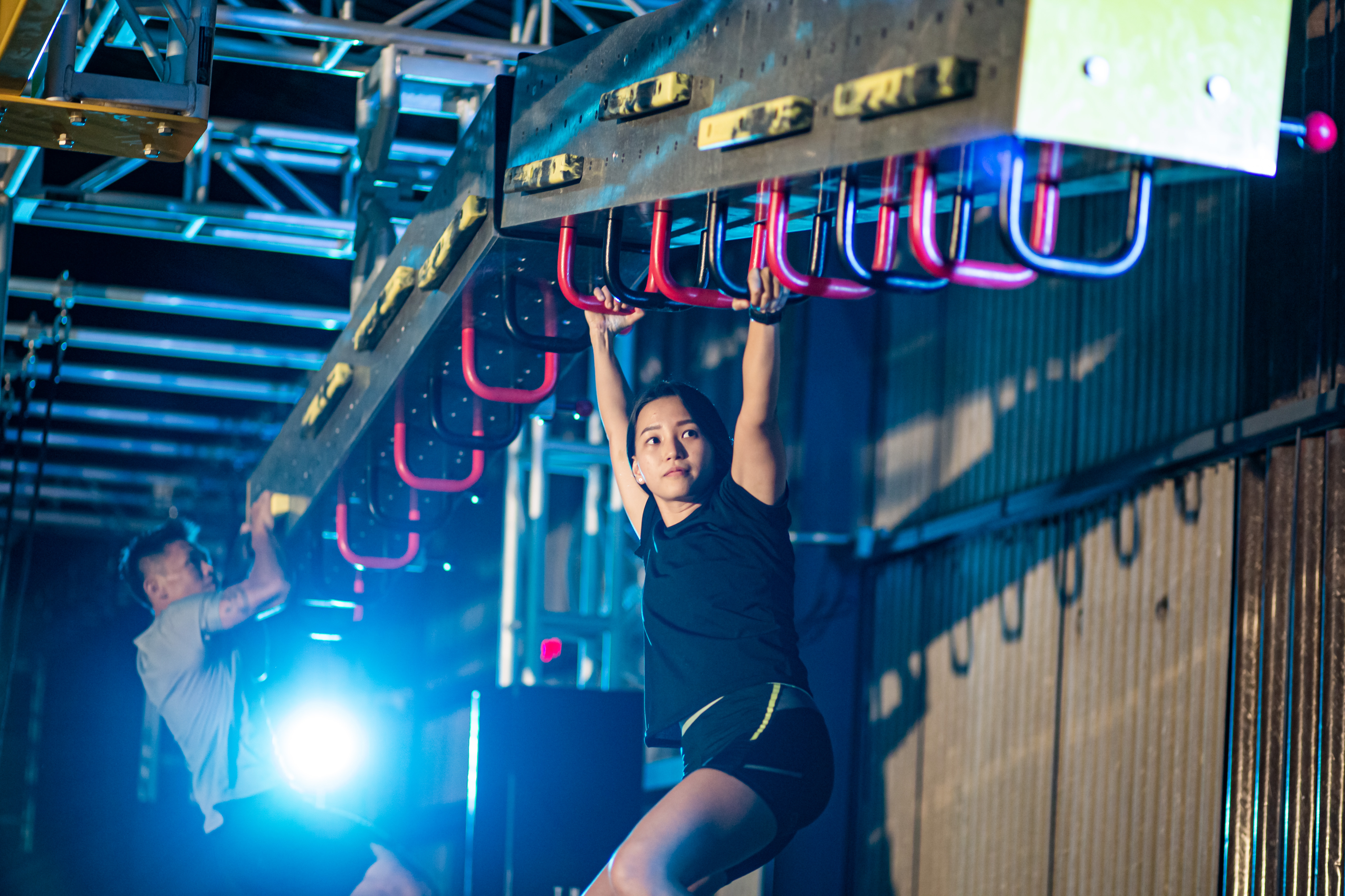 Asian Chinese partner athlete training in an obstacle course. Incline Monkey Bar, Cliff Hanger