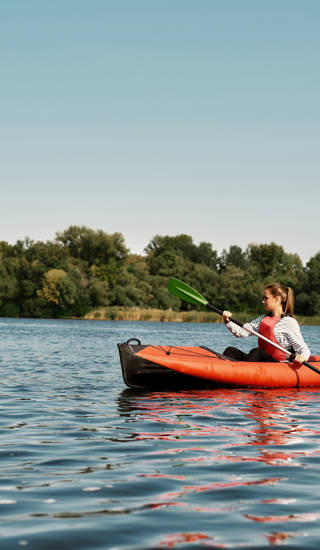 Young caucasian family floating on kayak with paddles. Concept of rest, leisure and vacation at nature. Extreme water sport. Mother, father and daughter wearing life vests. Summer sunny daytime