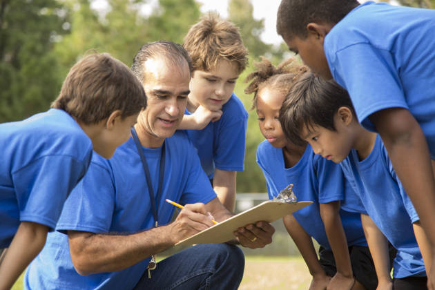 Multi culturele groep schoolkinderen luisteren naar hun coach