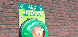 Waddinxveen, Netherlands - November 2020: Automated external defibrillator (AED) on a brick wall. Portable electronic first aid device to restore heart rhythm.