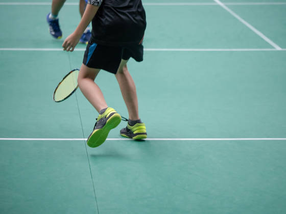 Man met badmintonracket op badmintonveld