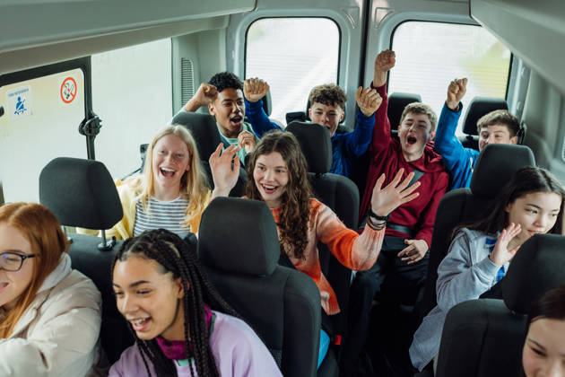 A high angle view of group of young teenage students enjoying the bus ride to a school field trip to Rothbury in Northumberland in the North East of England. They are singing and playing games to pass the time as they travel.