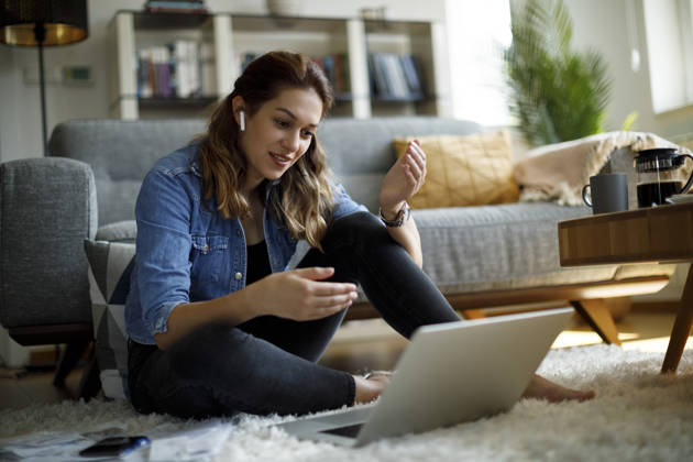 Smiling young woman with headphones having video call on laptop computer at home