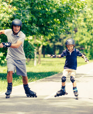 Vader en zoon rolschaatsen in park