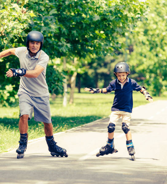 Vader en zoon rolschaatsen in park