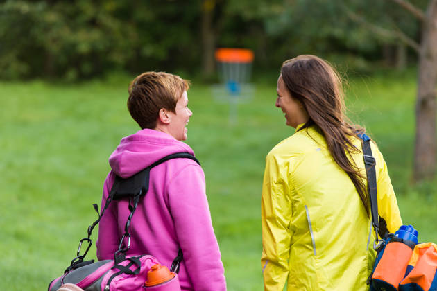Two disc golf players walking on the course