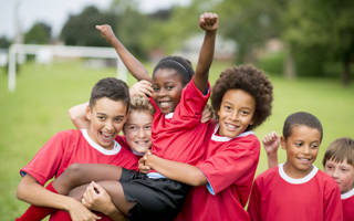 A group of children on a soccer team wearing red jerseys, celebrating their victory together.