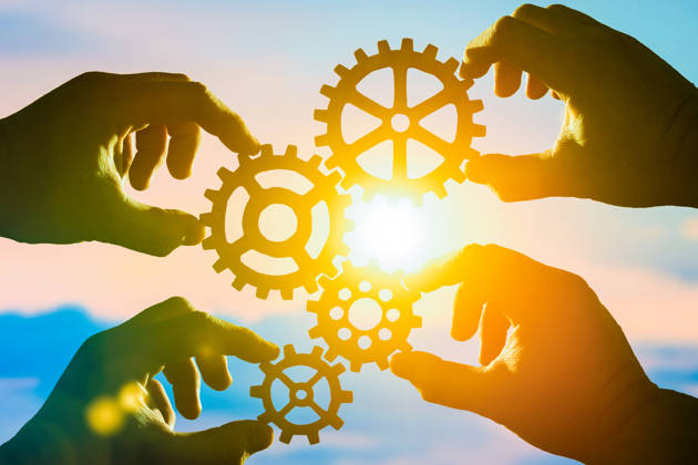 Four hands of businessmen collect puzzles from the gear in one mechanism. Collaboration, teamwork, strategy, creativity, innovation. The idea of a business concept.