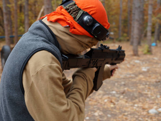 a teenager aiming aim at a laser gun while playing in the forest, rear view.