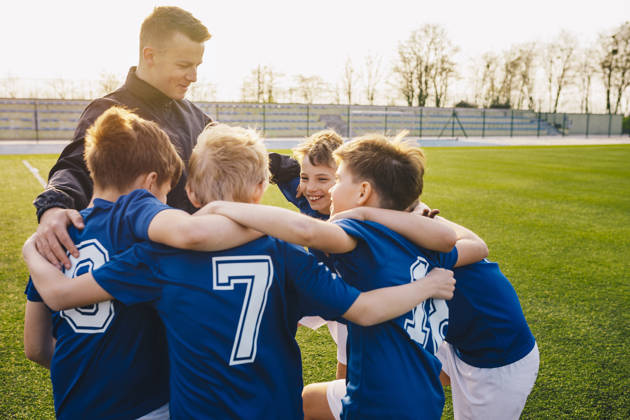 Groep voetballertjes viert overwinning samen met coach