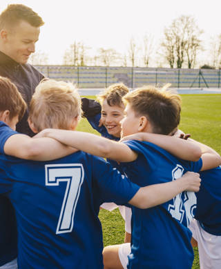 Groep voetballertjes viert overwinning samen met coach