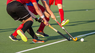 Twee hockeyspelers vechten om bal met stick