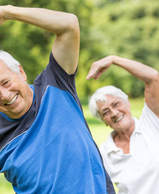 Drie senioren doen aan gymnastiek in het park