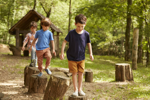 Multimove beeld van kleuters die wandelen op boomstammen