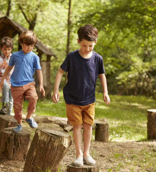 Multimove beeld van kleuters die wandelen op boomstammen