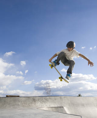 A young male on a skateboard catches some air in a skate park.
