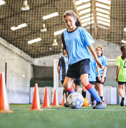 Meisje dribbelt met bal tussen kegels