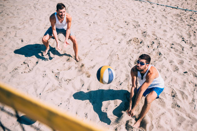 Luchtfoto van twee beachvolleyballers die bal over net slaan