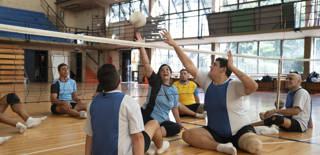 Several disabled athletes are training volley at an indoor court
