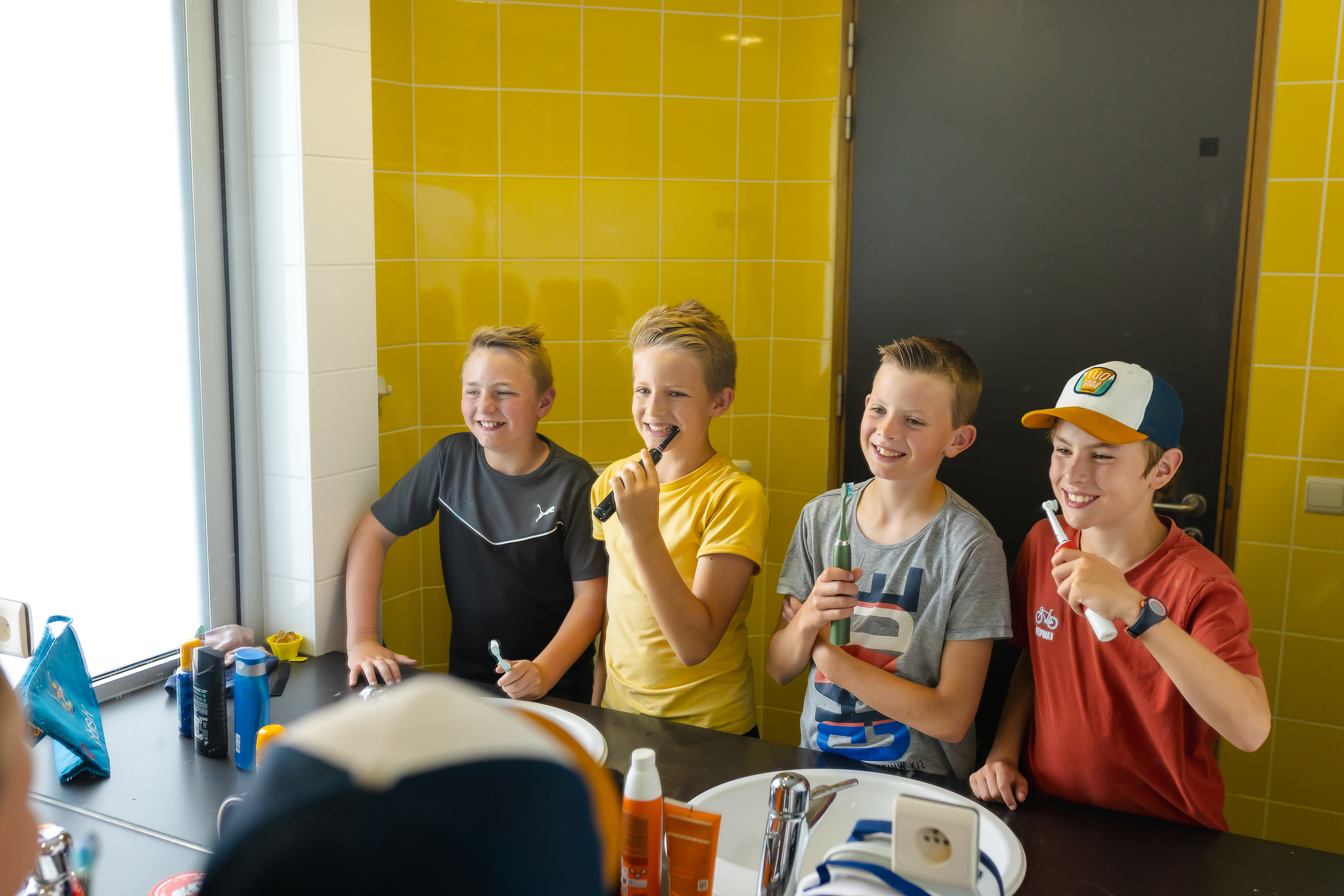 4 jongens poetsen hun tanden in de badkamer van het sportverblijf