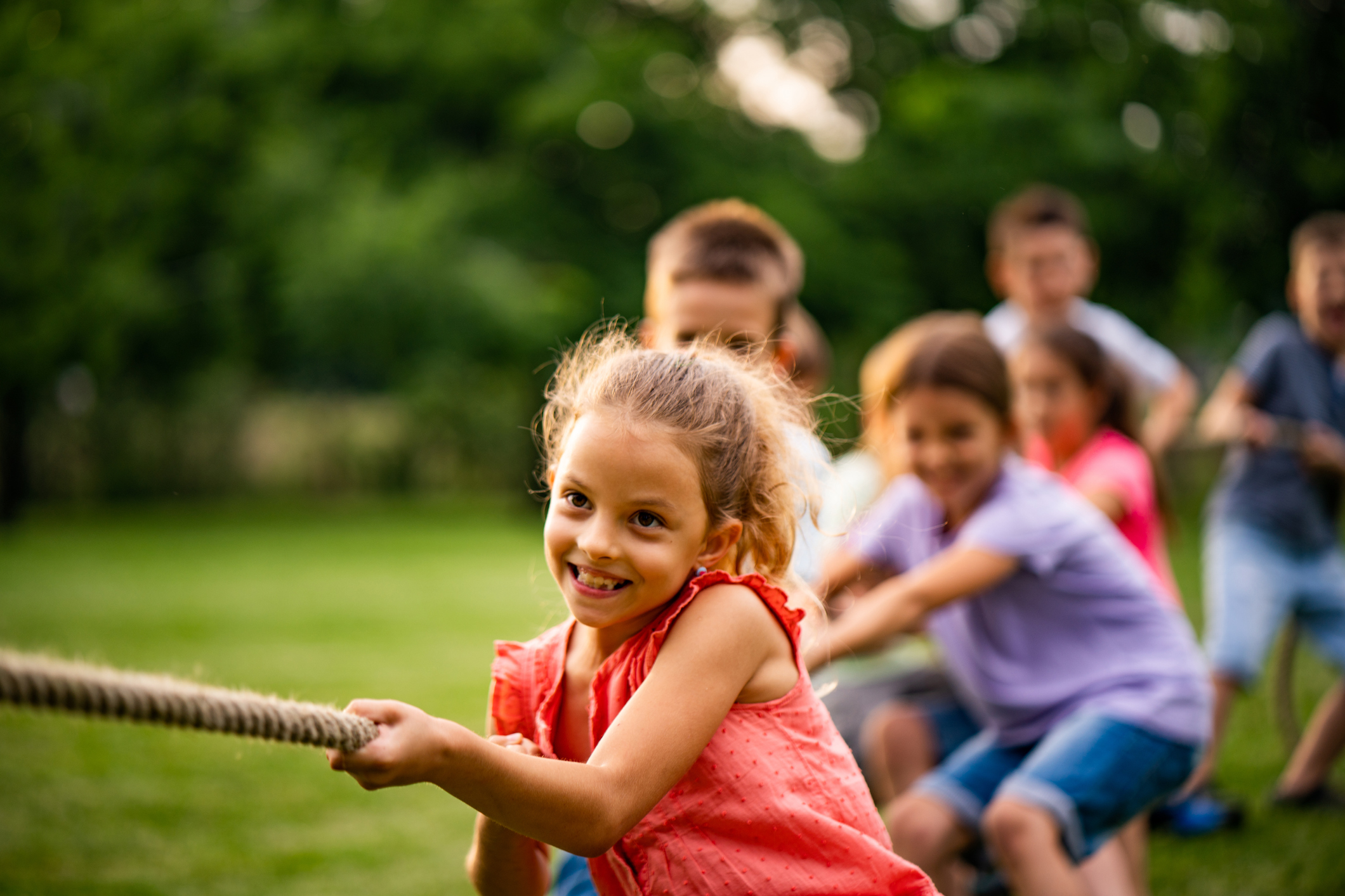 Happy kids pulling a rope in park
