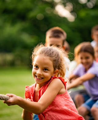 Happy kids pulling a rope in park