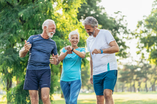 Three senior athletes in the park using digital devices after jogging