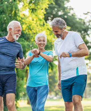 Three senior athletes in the park using digital devices after jogging