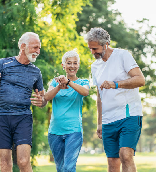 Three senior athletes in the park using digital devices after jogging