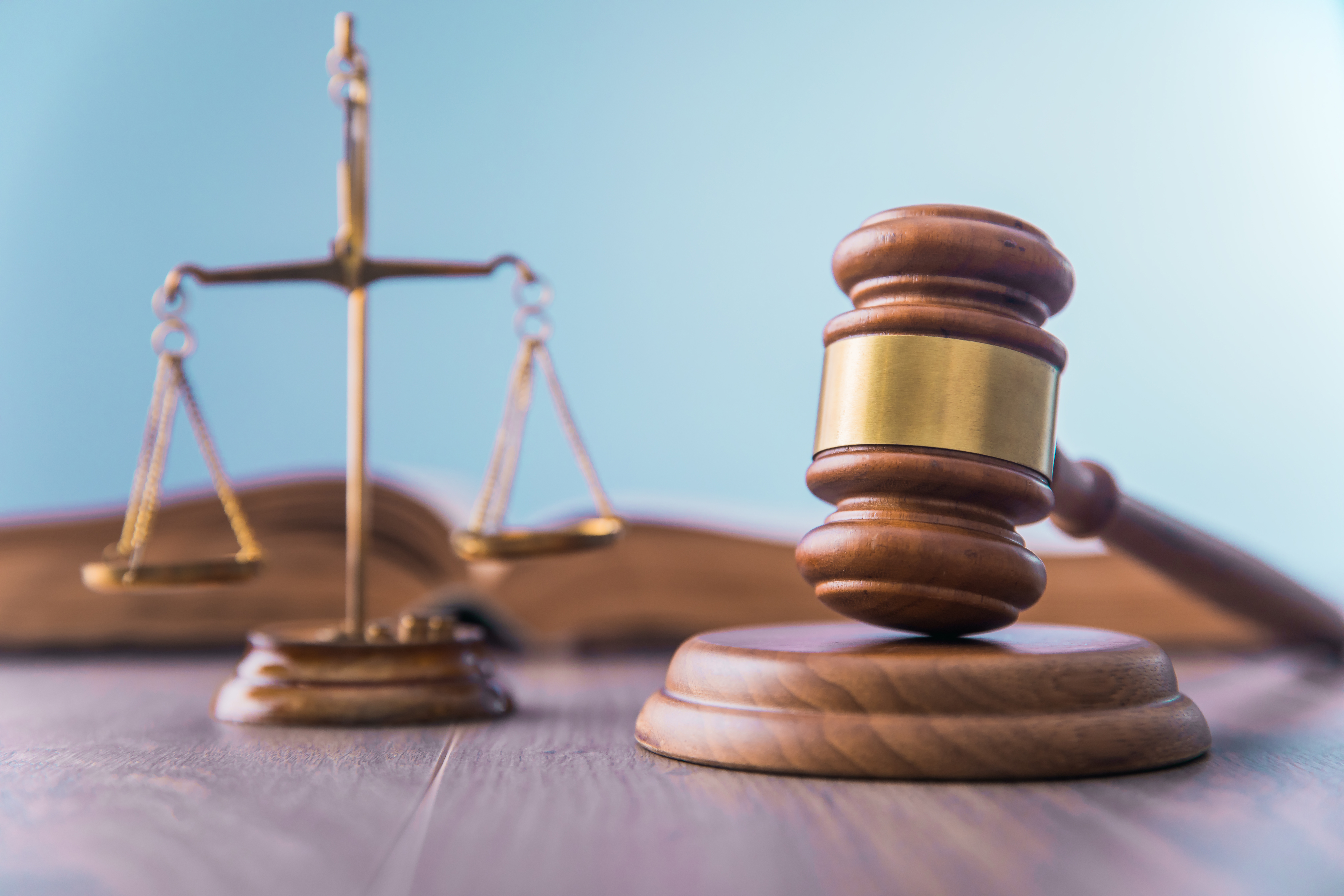 houten hamer op houten blok zoals gebruikt in de rechtzaal met weegschaal op de achtergrond