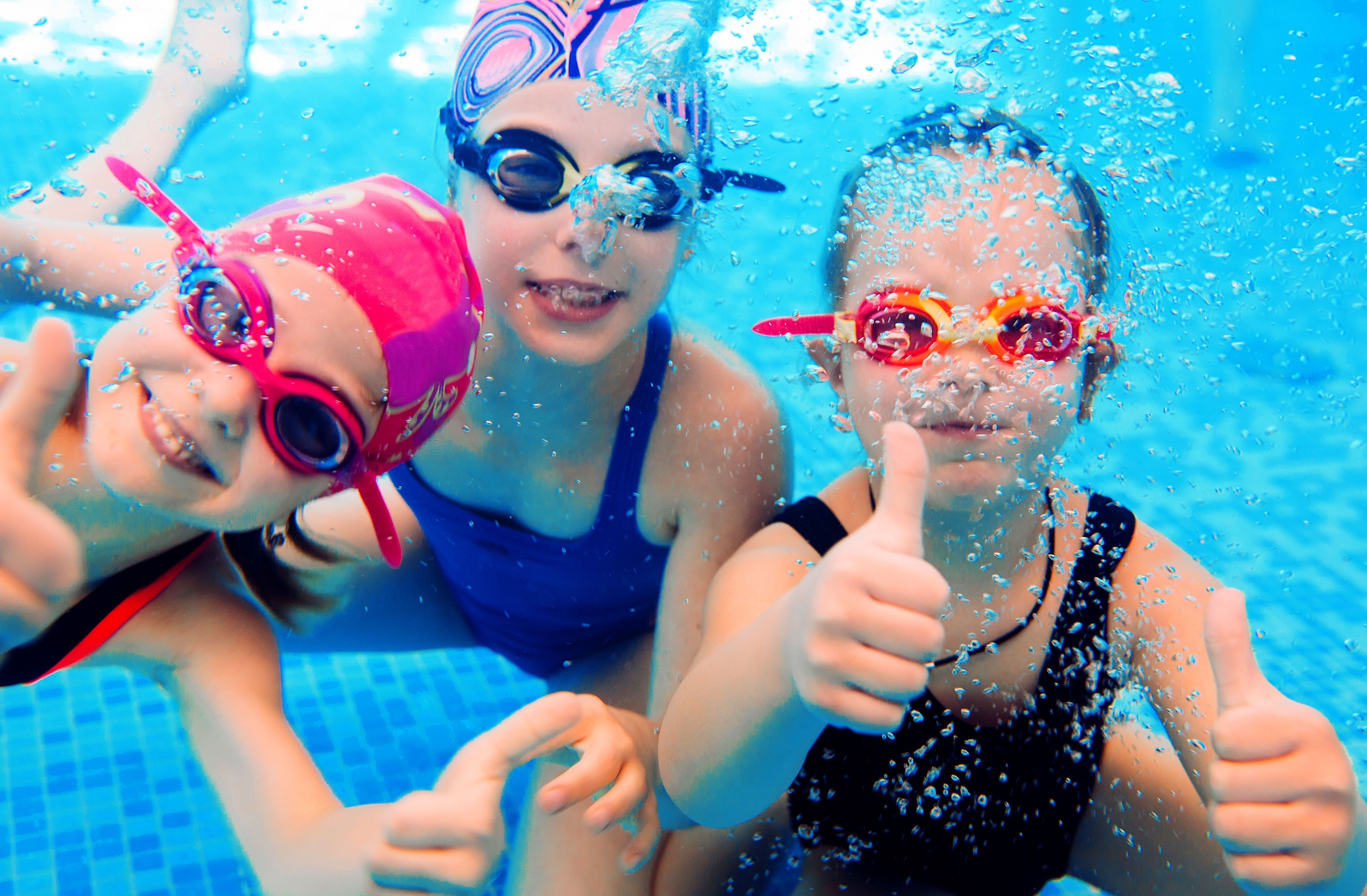 Underwater photo of young friends in swimming pool