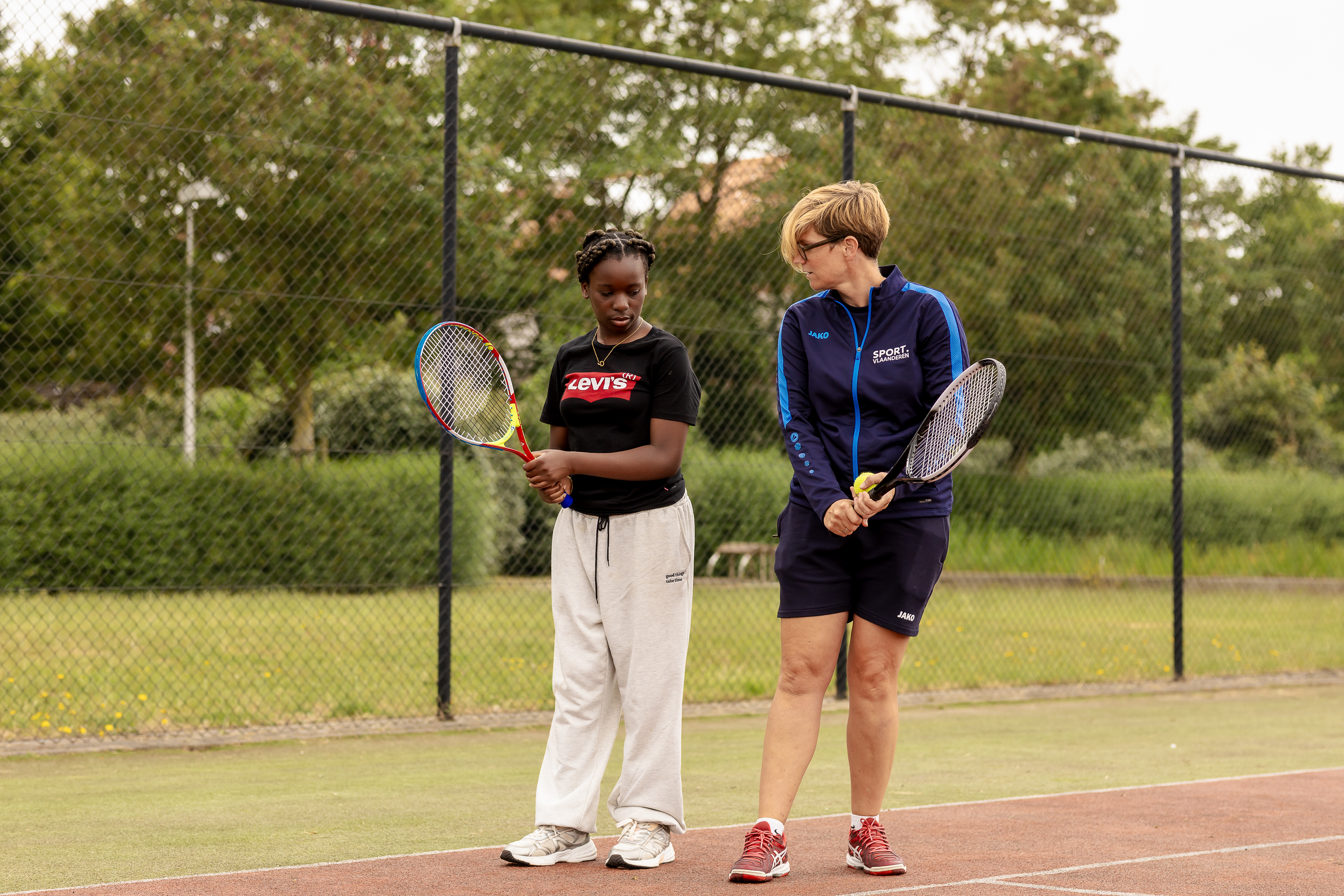 meisje krijgt tennisles van lesgever