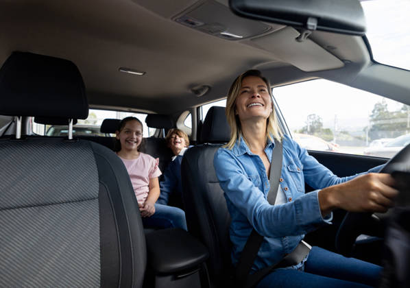 Happy Latin American mother driving her kids in the back seat of her car -Transportation concept