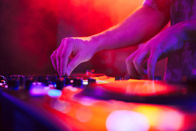 Close up of DJ hands on dj console mixer during concert in the night club
