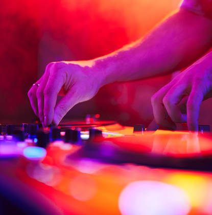 Close up of DJ hands on dj console mixer during concert in the night club