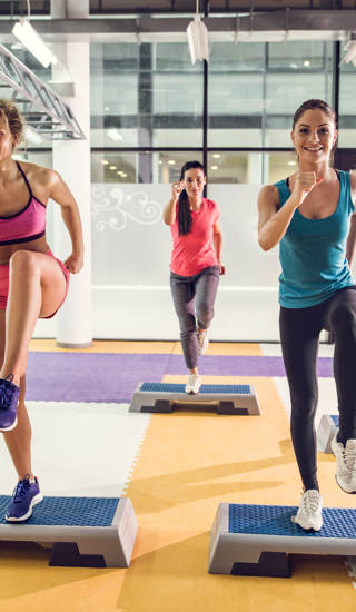 Gemengde groep jonge mensen doen step aerobics in zaal