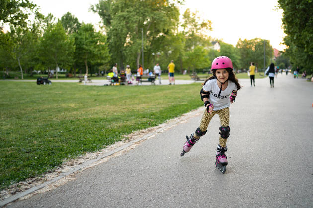Cute little girl riding on roller skate in public park